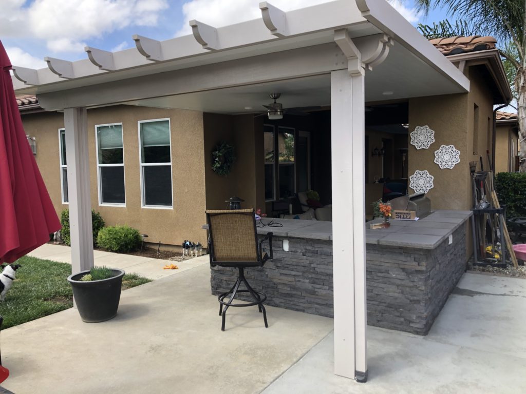 Outdoor kitchen and seating area under covered patio.